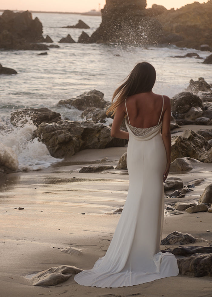 Model wears ivory cowl back wedding dress with beaded illusion details for her outdoor summer beach wedding