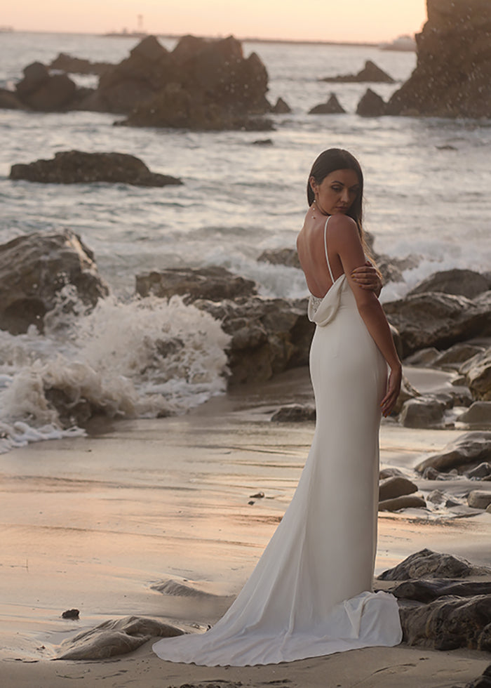 Bride wears Ivory Cowl back spaghetti strap fit and flare wedding dress on the beach