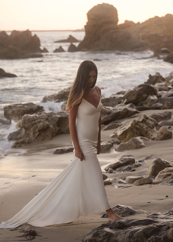 Bride wears ivory fit and flare cady gown with chapel train on the beach