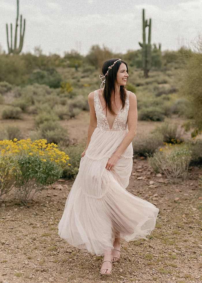 Bride playfully wears her soft A-line tulle wedding dress with deep v-neckline for outdoor desert wedding